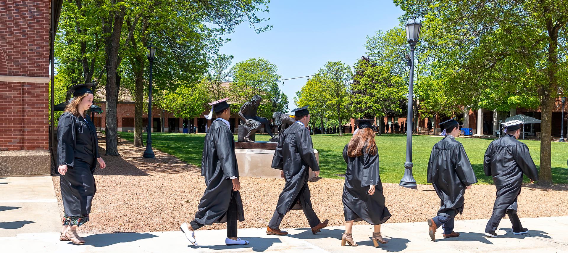 Grads processing past Divine Servant statue